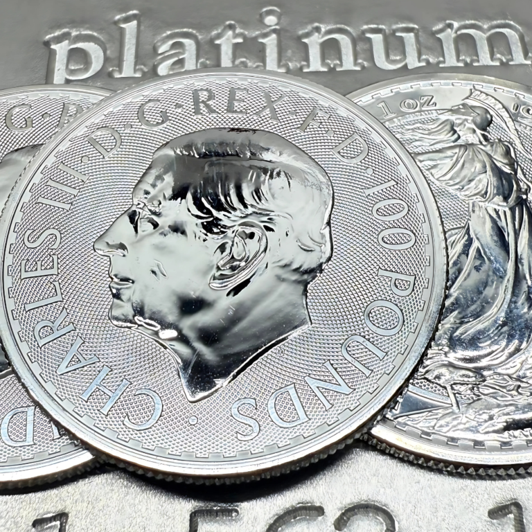 Detailaufnahme von Platinmünzen mit dem Porträt von King Charles III und einer Britannia-Münze auf einem Platinbarren
