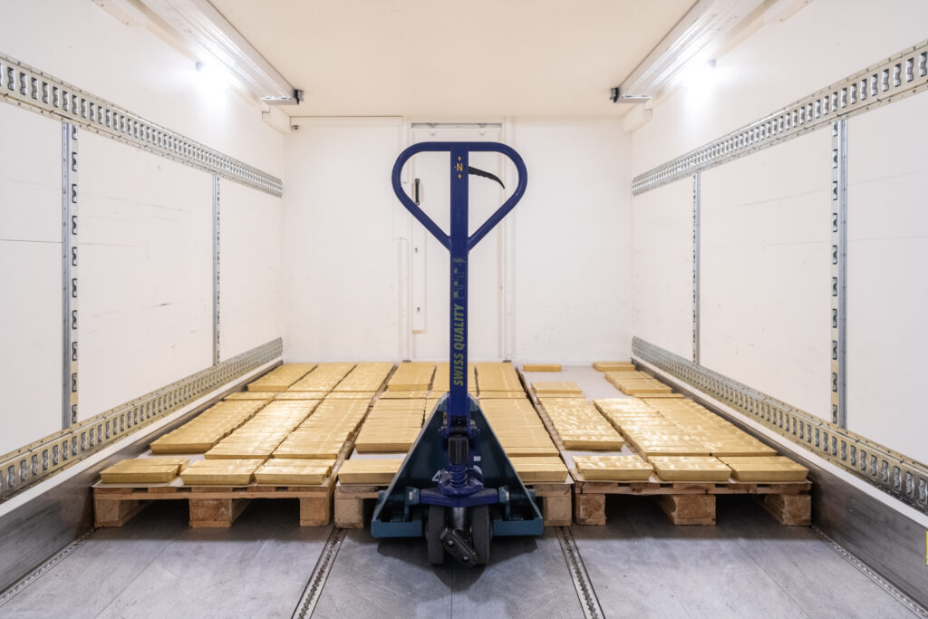 Paletten mit gestapelten Goldbarren in einem Sicherheitsraum von Helveticor, bereit für den Transport mit einem Hubwagen