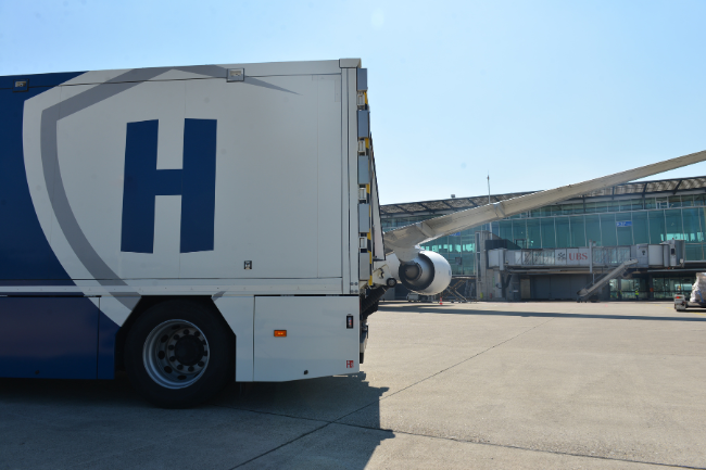 Spezialfahrzeug von Helveticor vor einem Flugzeug auf dem Rollfeld eines Flughafens – Symbol für sichere Edelmetalltransporte weltweit