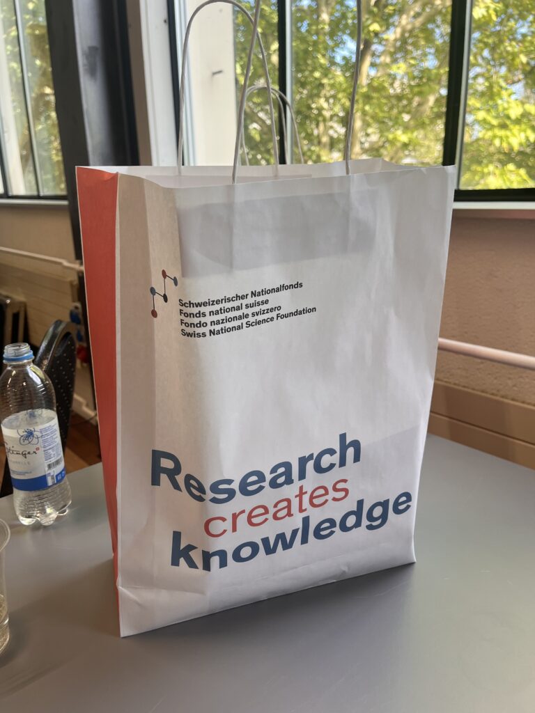 Papiertasche mit der Aufschrift "Research creates knowledge" auf einer Konferenz