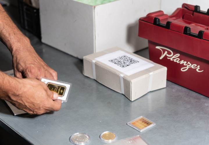 Pick & Pack: Edelmetallbarren und Münzen werden für den Versand vorbereitet – Planzer Box im Hintergrund